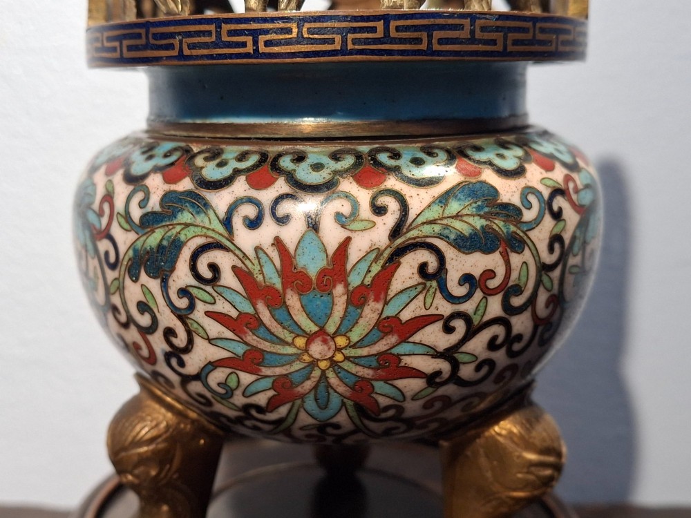 A 19th-century Chinese tripod cloisonne enamel censer featuring intricate floral scrollwork, upright loop handles, three gilded cabriole feet, and a pierced brass cover. View VII
