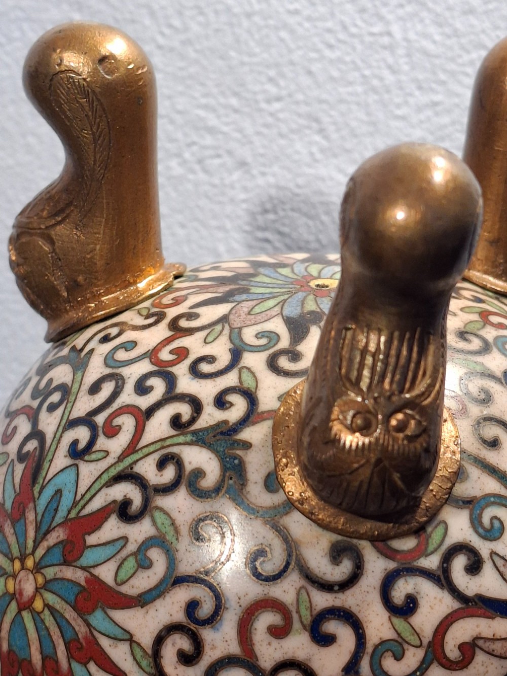 A 19th-century Chinese tripod cloisonne enamel censer featuring intricate floral scrollwork, upright loop handles, three gilded cabriole feet, and a pierced brass cover. View XII