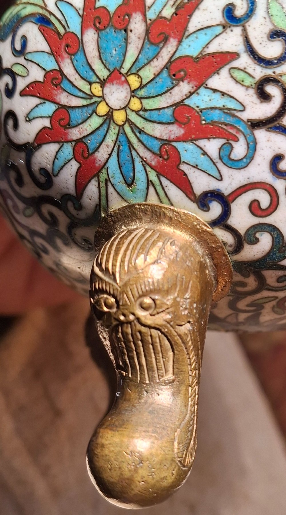 A 19th-century Chinese tripod cloisonne enamel censer featuring intricate floral scrollwork, upright loop handles, three gilded cabriole feet, and a pierced brass cover. View XIV