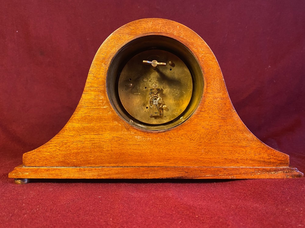 An Edwardian satinwood mantel clock featuring an arched case with geometric cross marquetry, a white Roman numeral dial, and a brass bezel. View IV