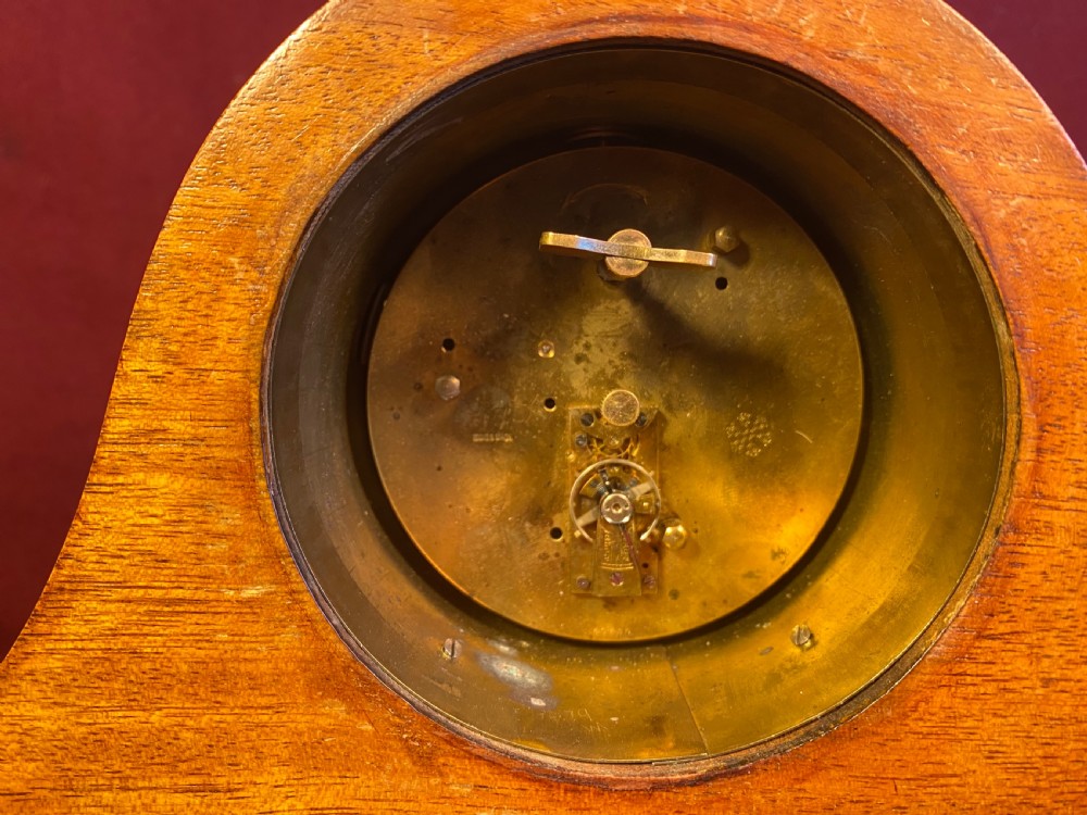 An Edwardian satinwood mantel clock featuring an arched case with geometric cross marquetry, a white Roman numeral dial, and a brass bezel. View V