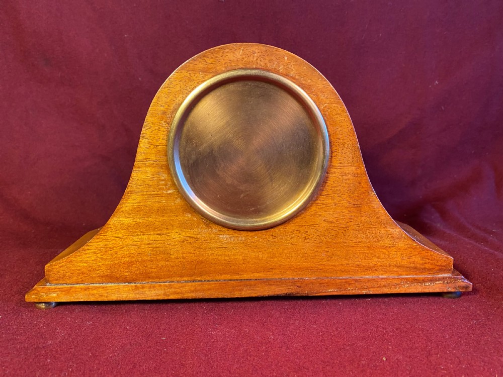 An Edwardian satinwood mantel clock featuring an arched case with geometric cross marquetry, a white Roman numeral dial, and a brass bezel. View VI