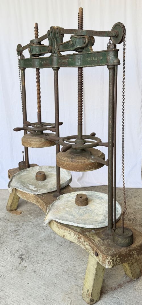 A Victorian double cheese press with a painted dark green cast-iron upper frame, twin screw spindles, and a heavy wooden base structure. View VI