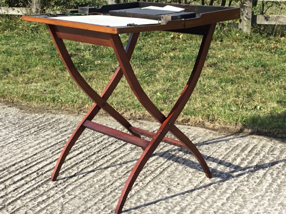 A mahogany folding coaching table with curved X-frame legs and a tray top design. View X