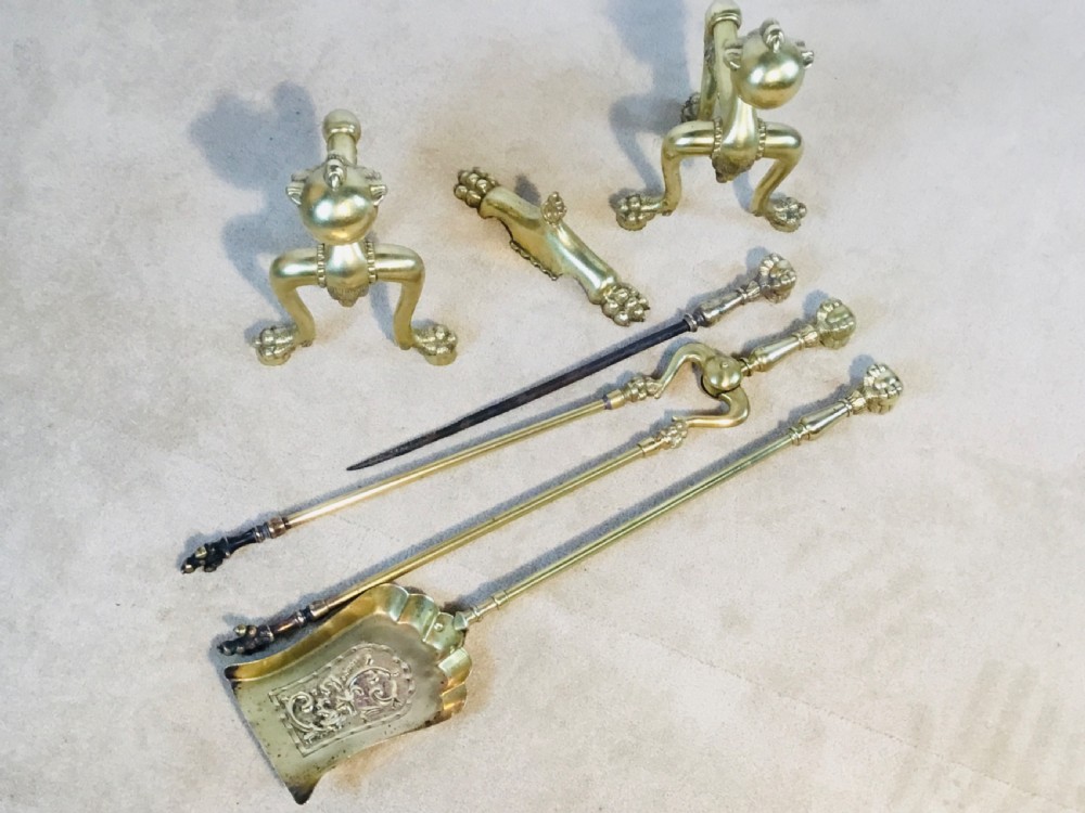 A polished brass fireside suite including a fender, two fire dogs with claw and ball feet, and three matching companion tools. View IX