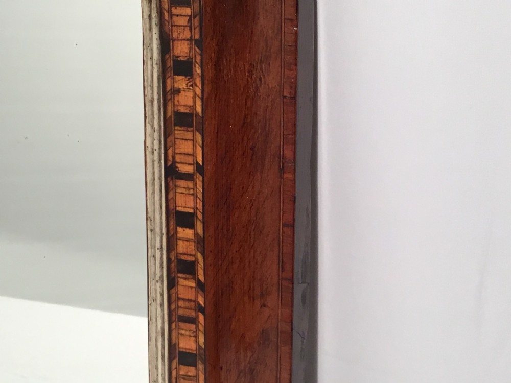 A Victorian walnut overmantel mirror featuring a low rectangular frame with rounded top corners, detailed geometric wood inlay, and a gilded inner slip surrounding a reflective mirror plate. View VII
