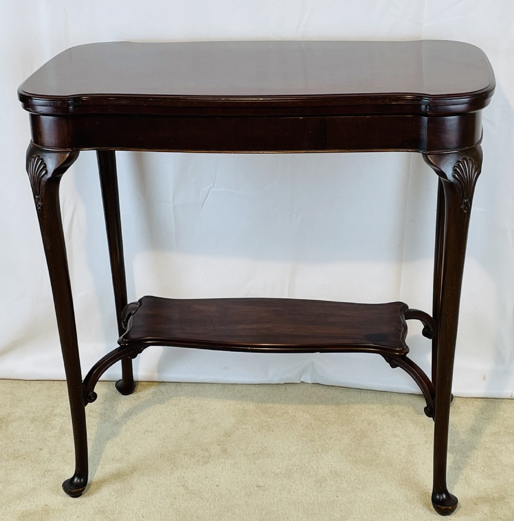 A dark mahogany Queen Anne style fold-over card table featuring cabriole legs with shell-carved knees and a lower stretcher shelf. View V