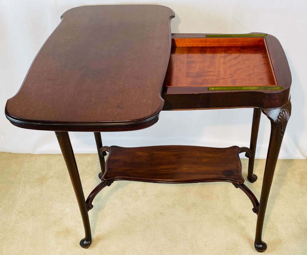 A dark mahogany Queen Anne style fold-over card table featuring cabriole legs with shell-carved knees and a lower stretcher shelf. View VI