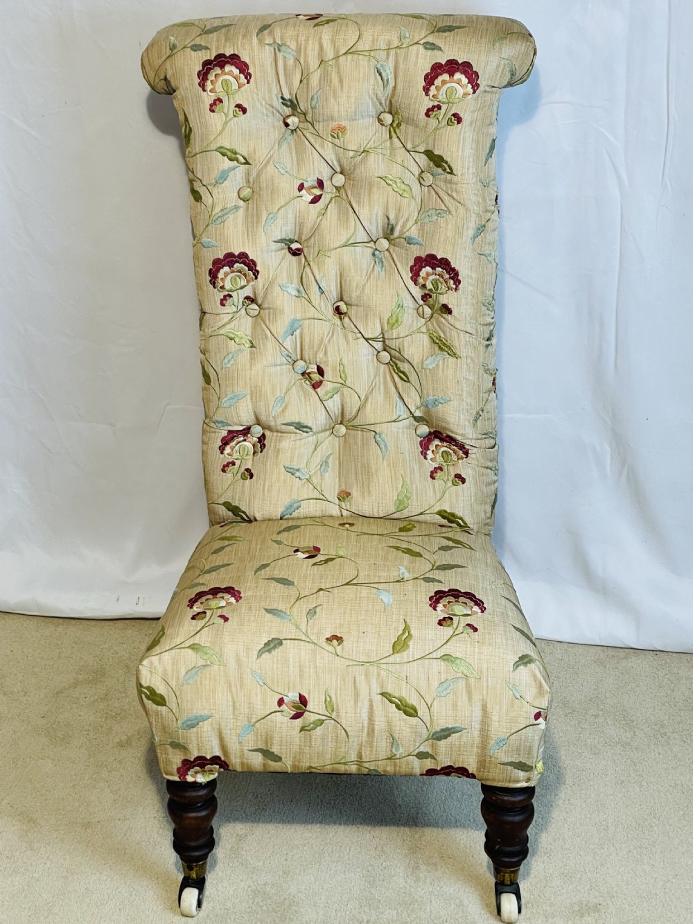 A Victorian Prie-Dieu chair featuring button-tufted cream upholstery with floral embroidery, supported on turned dark wood legs with ceramic castors. View III