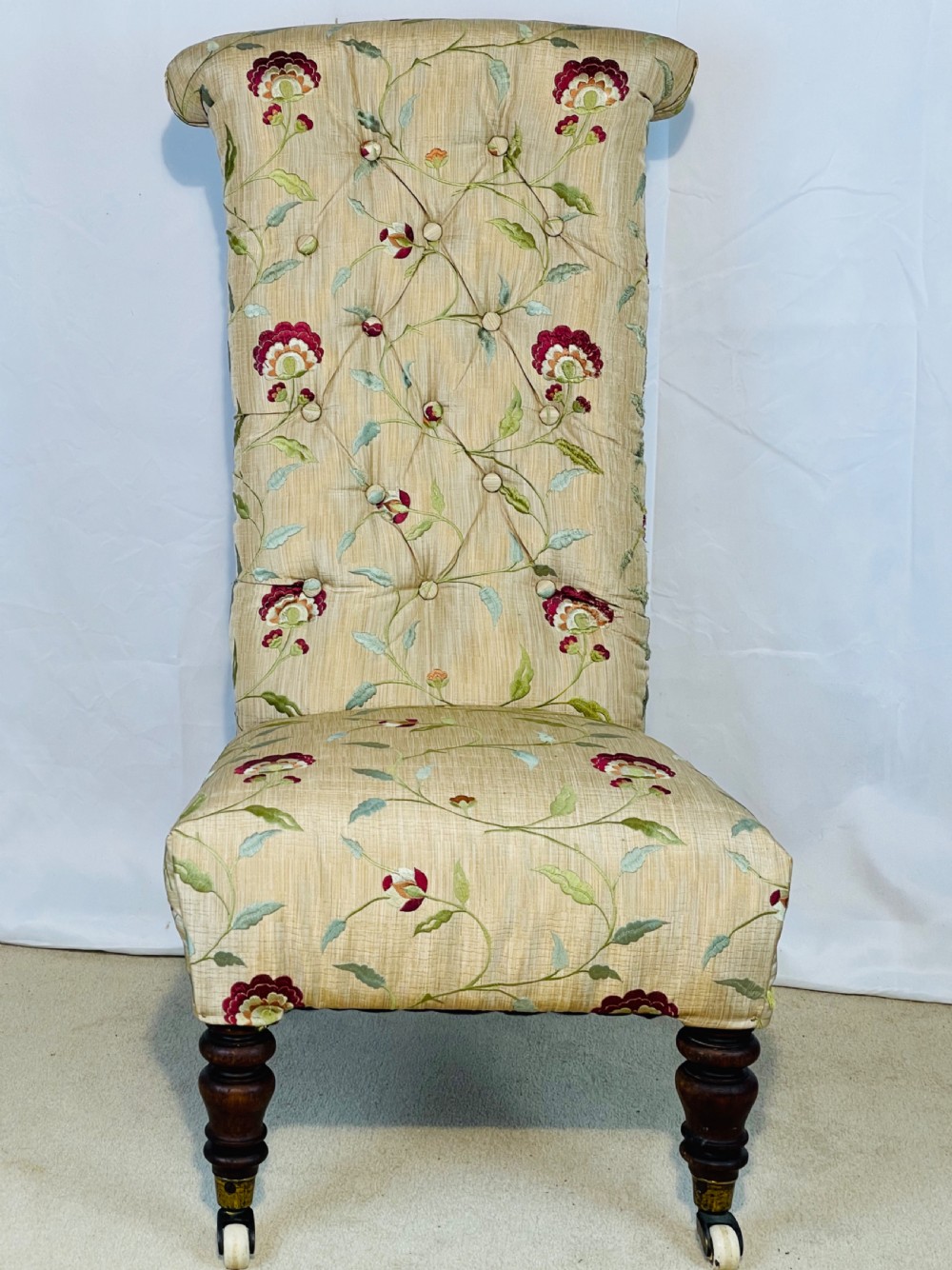 A Victorian Prie-Dieu chair featuring button-tufted cream upholstery with floral embroidery, supported on turned dark wood legs with ceramic castors. View XII