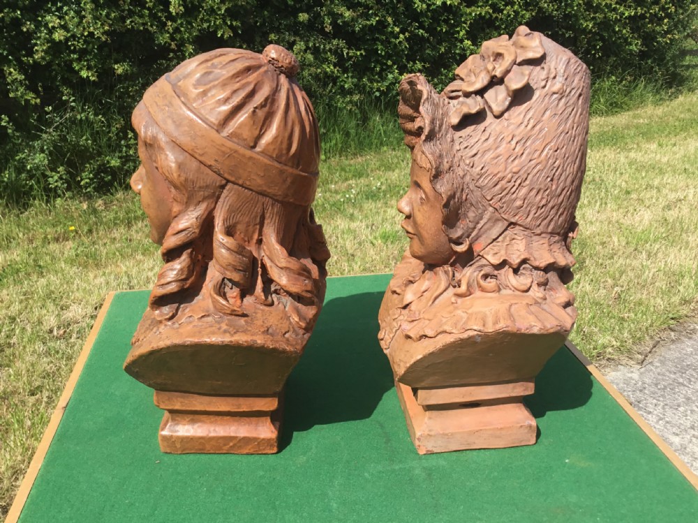 A pair of 19th-century terracotta portrait busts depicting a young boy wearing a cap and a young girl wearing a frilled bonnet. View II