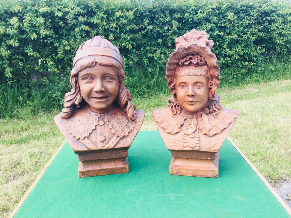 A pair of 19th-century terracotta portrait busts depicting a young boy wearing a cap and a young girl wearing a frilled bonnet. View VI
