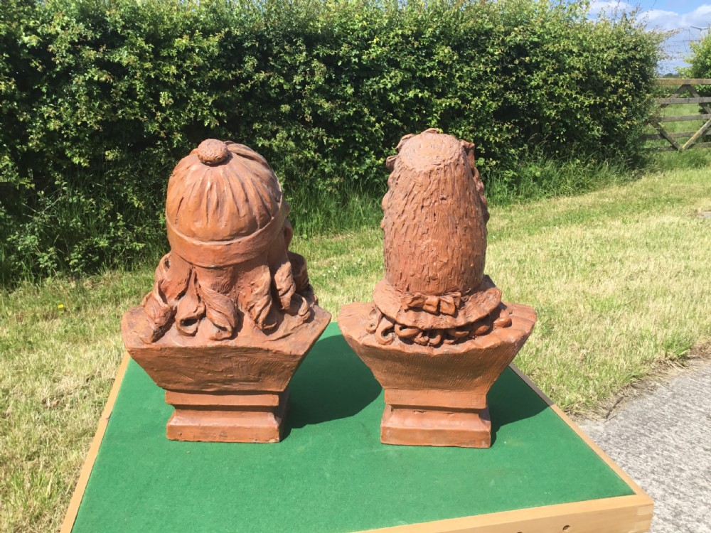 A pair of 19th-century terracotta portrait busts depicting a young boy wearing a cap and a young girl wearing a frilled bonnet. View XI
