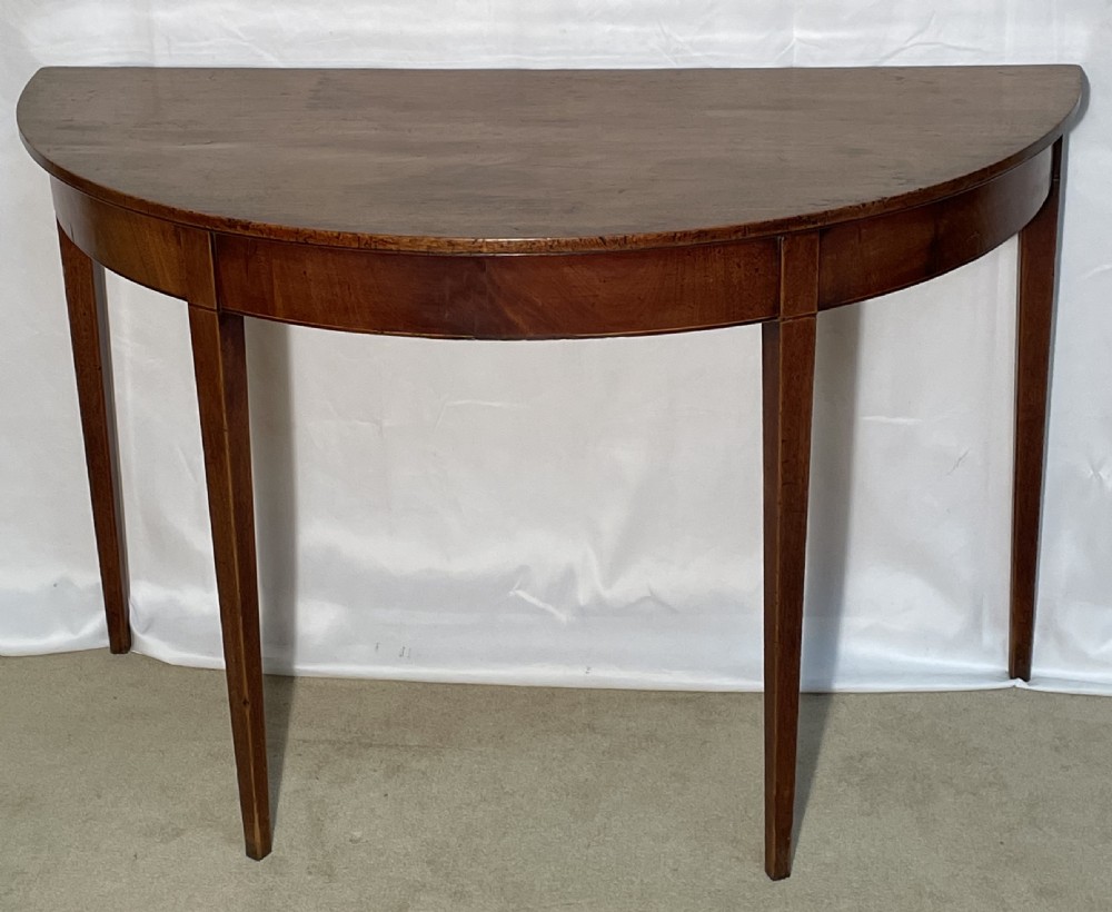 A Georgian mahogany extension dining table featuring a round top assembled from two demi-lune end sections and a central leaf, supported by slender square tapered legs. View V