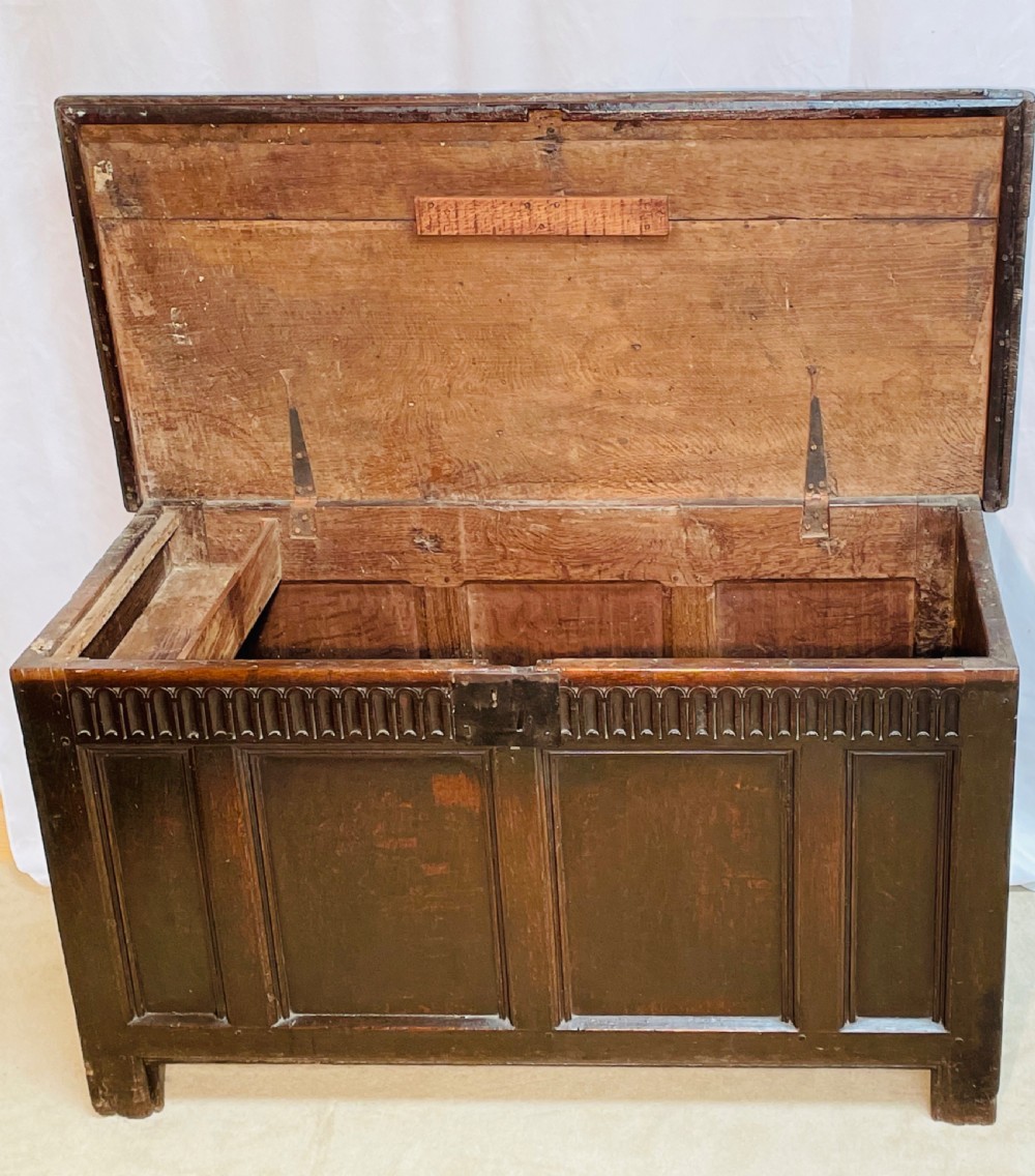 An 18th-century dark oak coffer with a carved upper border and recessed front panels. View II