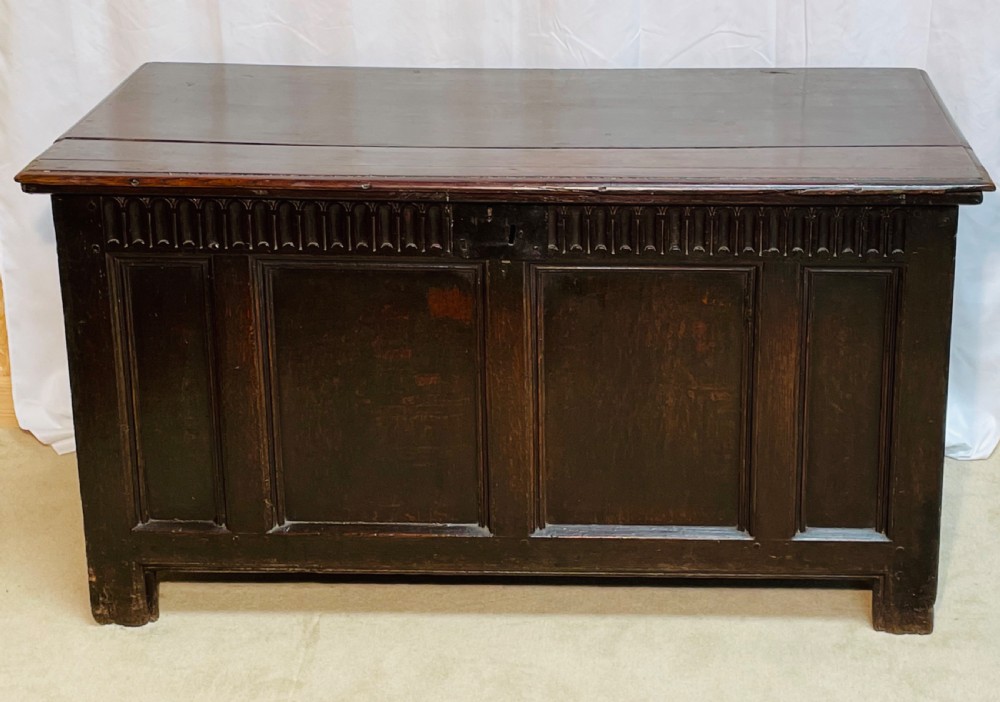 An 18th-century dark oak coffer with a carved upper border and recessed front panels. View III