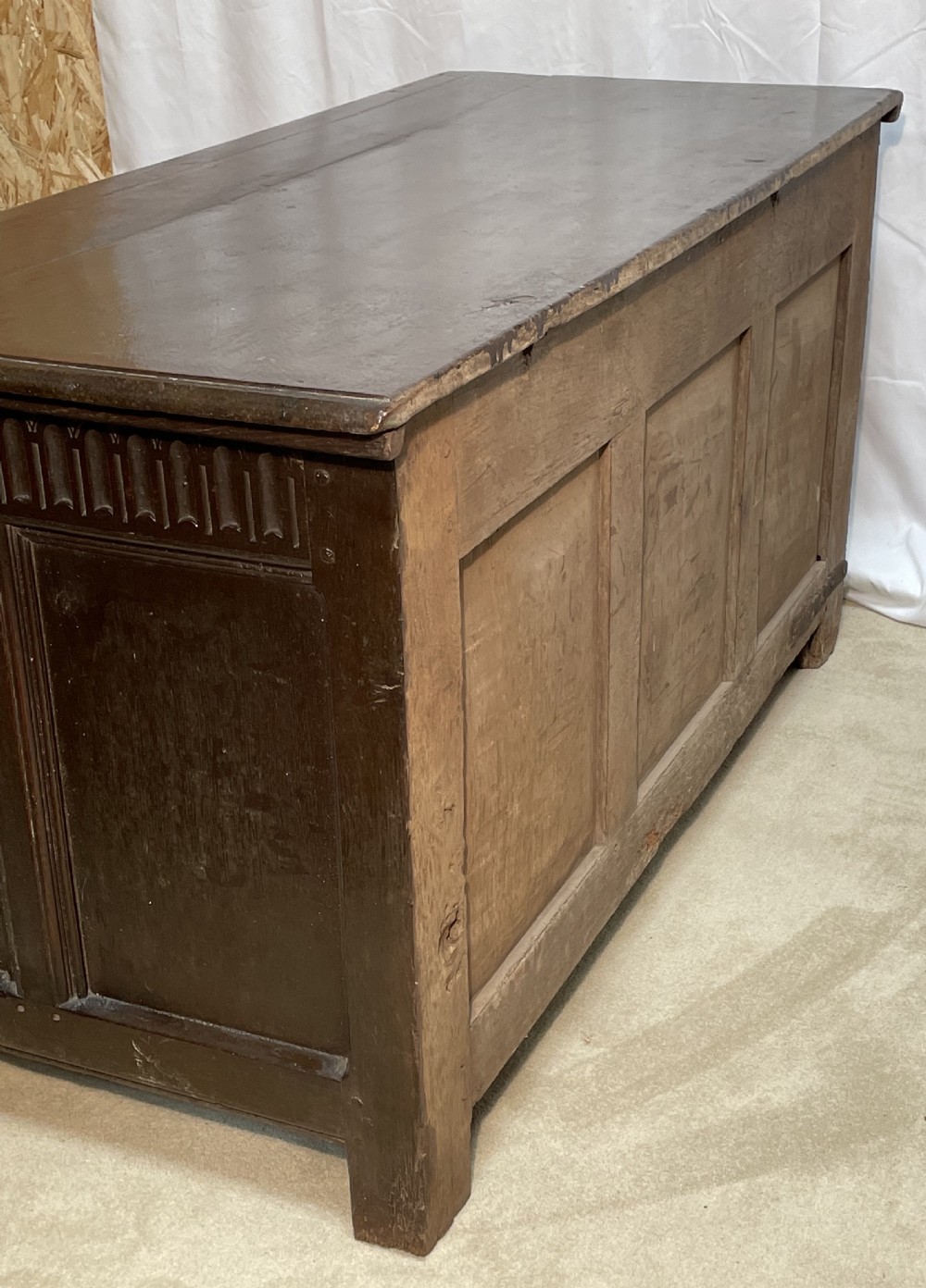 An 18th-century dark oak coffer with a carved upper border and recessed front panels. View VII