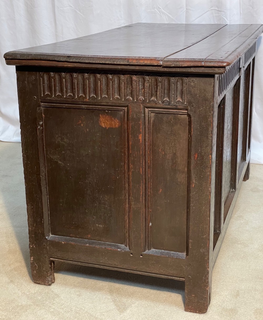 An 18th-century dark oak coffer with a carved upper border and recessed front panels. View VIII