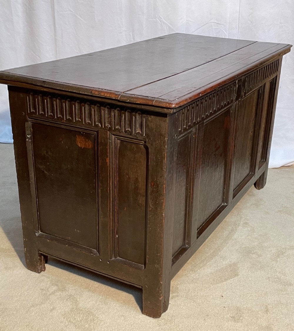An 18th-century dark oak coffer with a carved upper border and recessed front panels. View IX