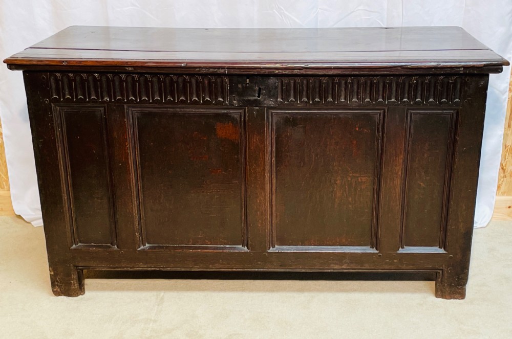 An 18th-century dark oak coffer with a carved upper border and recessed front panels. View XIV