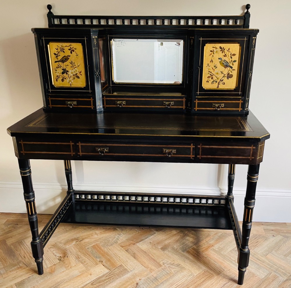 An ebonised Aesthetic Movement bonheur du jour featuring gold line detailing, central mirror, two hand-painted bird panels on small upper cabinets, and turned legs with a spindle lower gallery. View VI