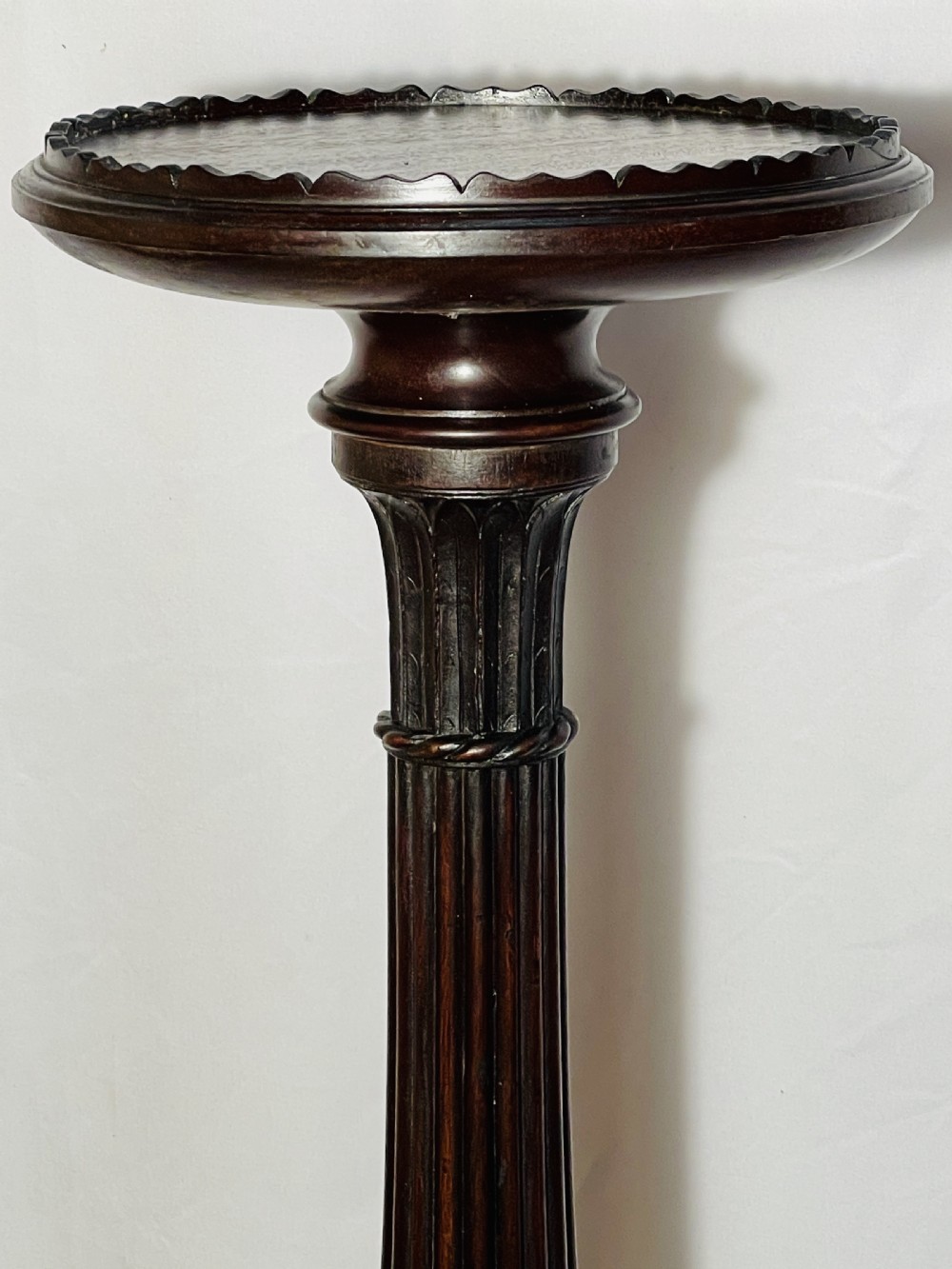 A tall dark mahogany torchere stand with a carved circular top, fluted central column, and tripod base with claw-and-ball feet. View VII