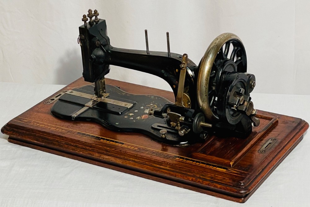 A late nineteenth-century black cast iron Gritzner sewing machine with floral decals mounted on an inlaid wooden base.