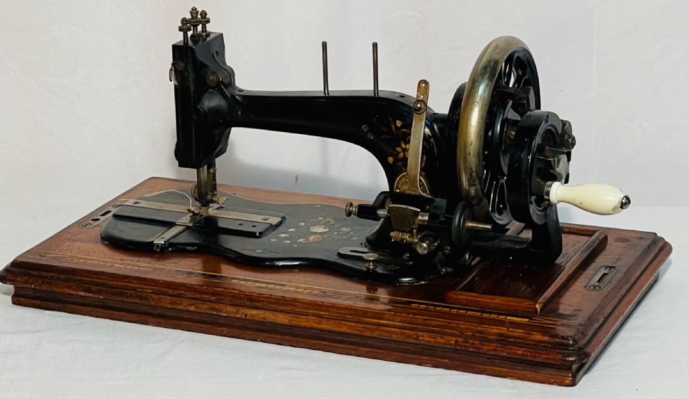 A late nineteenth-century black cast iron Gritzner sewing machine with floral decals mounted on an inlaid wooden base. View V