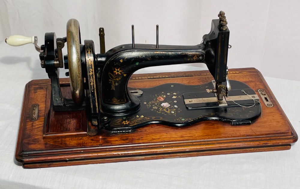 A late nineteenth-century black cast iron Gritzner sewing machine with floral decals mounted on an inlaid wooden base. View VIII