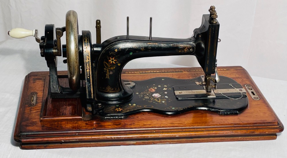 A late nineteenth-century black cast iron Gritzner sewing machine with floral decals mounted on an inlaid wooden base. View IX