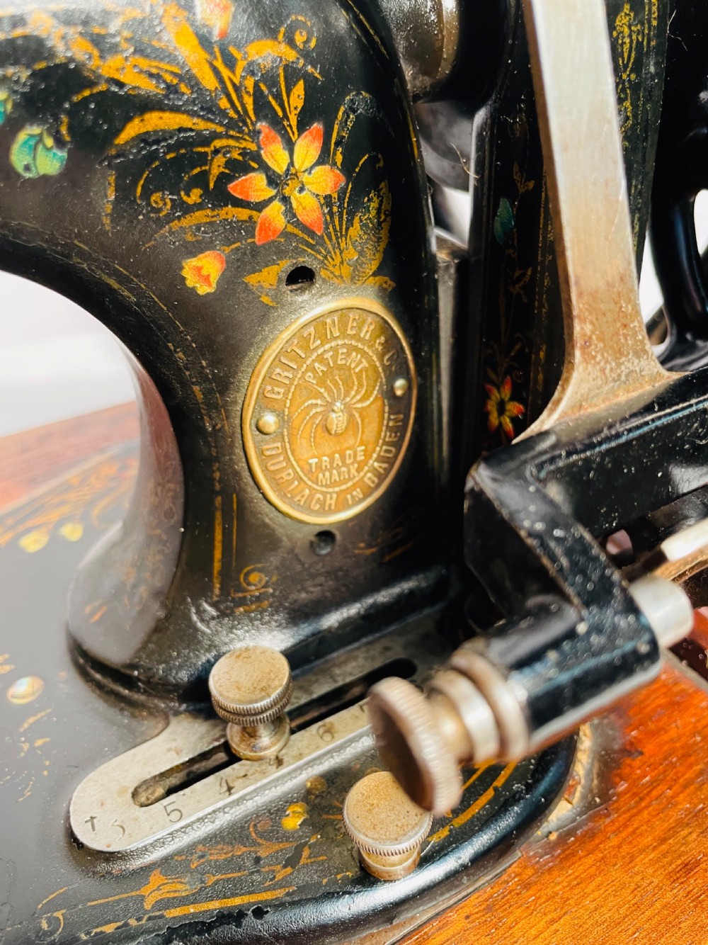 A late nineteenth-century black cast iron Gritzner sewing machine with floral decals mounted on an inlaid wooden base. View X