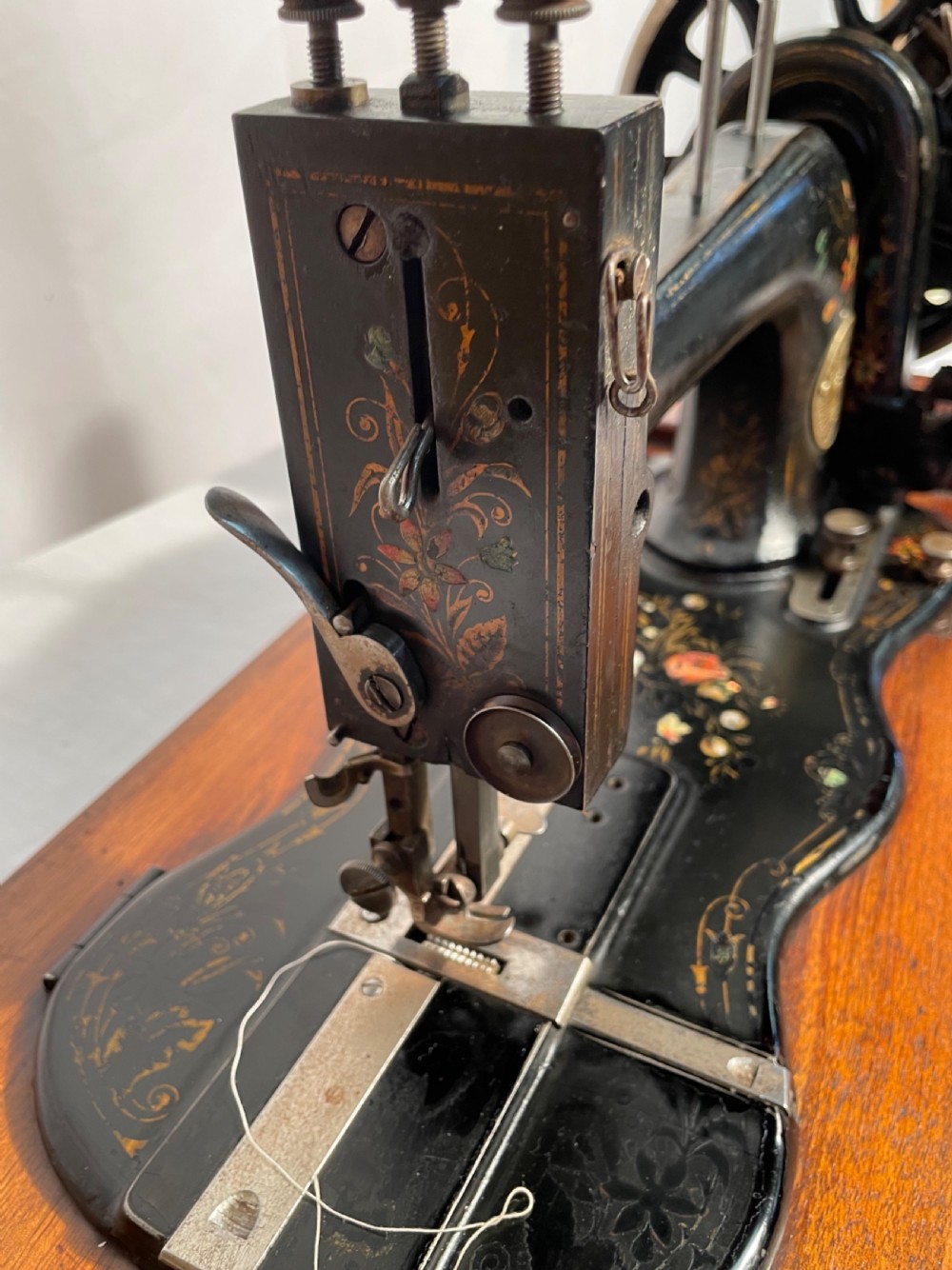A late nineteenth-century black cast iron Gritzner sewing machine with floral decals mounted on an inlaid wooden base. View XI
