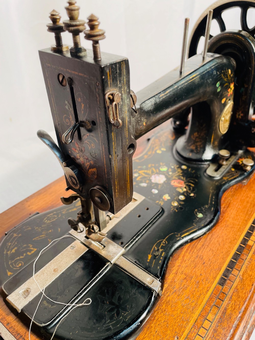 A late nineteenth-century black cast iron Gritzner sewing machine with floral decals mounted on an inlaid wooden base. View XII