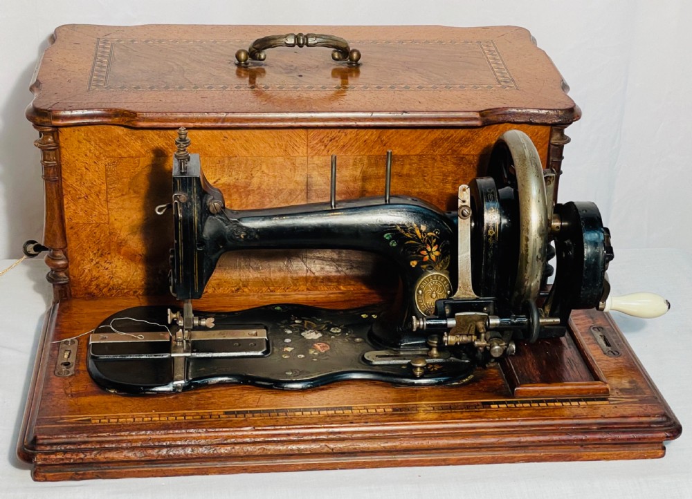 A late nineteenth-century black cast iron Gritzner sewing machine with floral decals mounted on an inlaid wooden base. View XIV