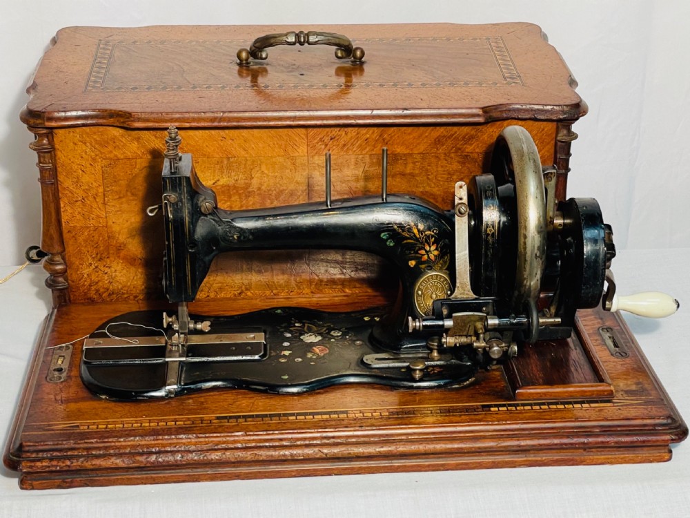 A late nineteenth-century black cast iron Gritzner sewing machine with floral decals mounted on an inlaid wooden base. View XV
