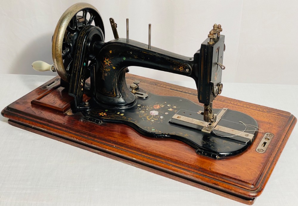 A late nineteenth-century black cast iron Gritzner sewing machine with floral decals mounted on an inlaid wooden base. View XVI