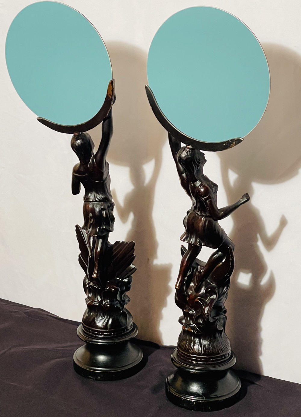 A pair of dark patinated spelter table mirrors featuring classical female figures standing on celestial-themed bases holding circular glass mirrors above their heads. View IX