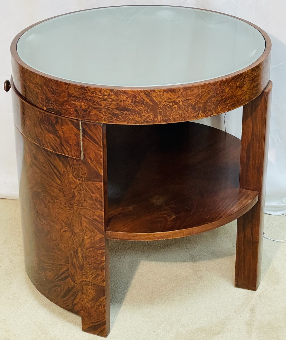 A circular Art Deco occasional table made from rich burr walnut veneer featuring an inset illuminated frosted glass top, curved side door, and lower shelf. View III