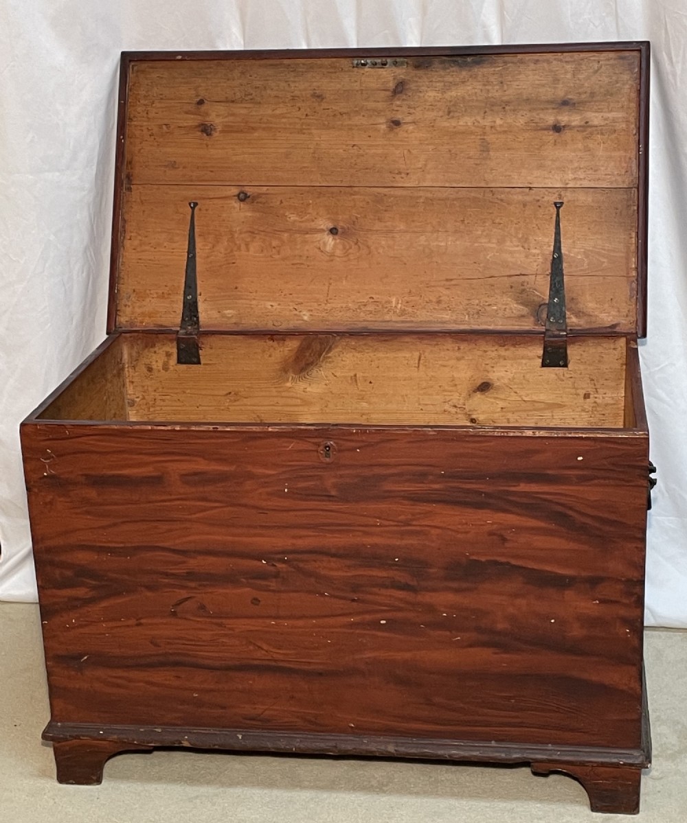 A nineteenth-century rectangular pine blanket box with a reddish-brown painted finish, hinged lid, keyhole, and bracket feet. View II