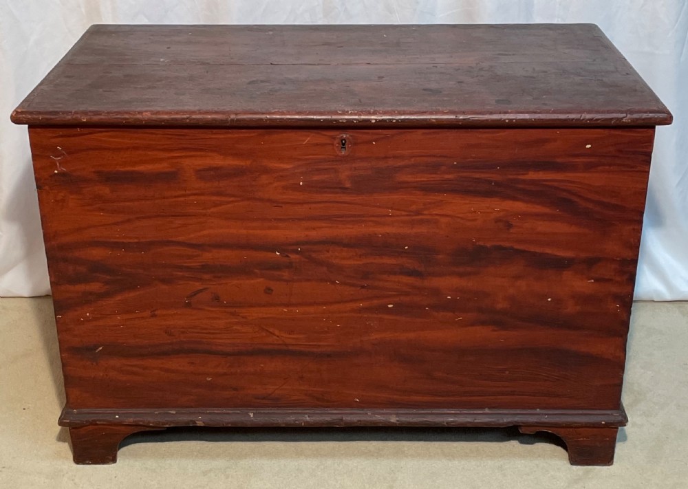 A nineteenth-century rectangular pine blanket box with a reddish-brown painted finish, hinged lid, keyhole, and bracket feet. View VI