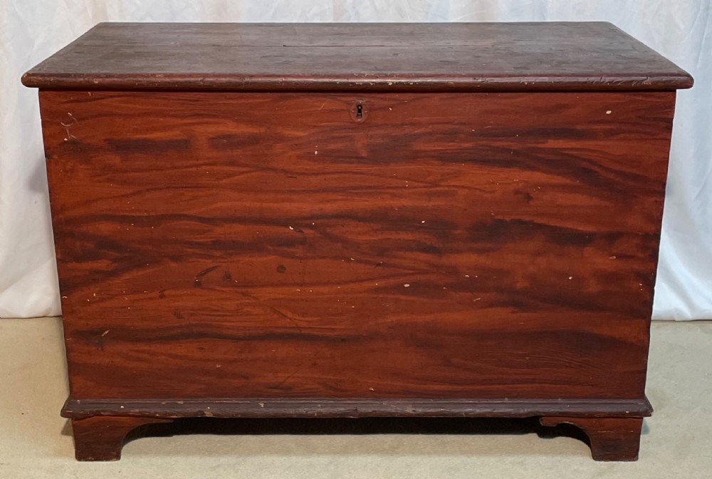 A nineteenth-century rectangular pine blanket box with a reddish-brown painted finish, hinged lid, keyhole, and bracket feet. View VIII