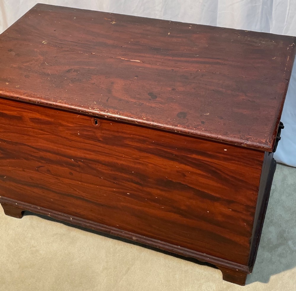 A nineteenth-century rectangular pine blanket box with a reddish-brown painted finish, hinged lid, keyhole, and bracket feet. View IX