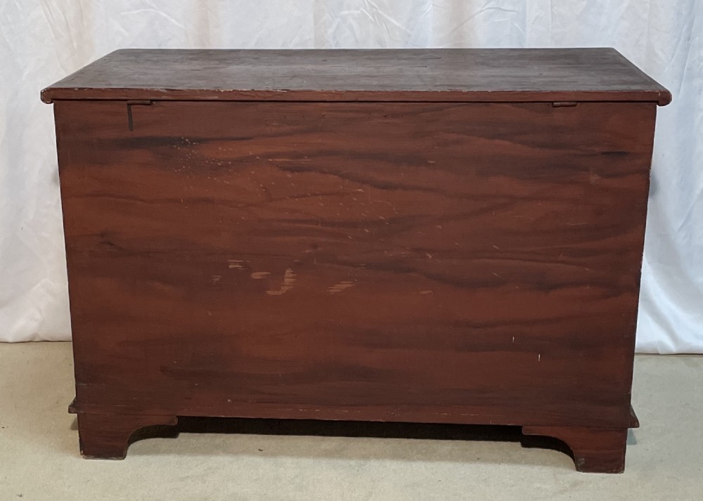 A nineteenth-century rectangular pine blanket box with a reddish-brown painted finish, hinged lid, keyhole, and bracket feet. View XII