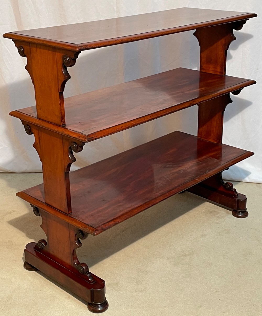 A three-tiered William IV mahogany dumb waiter featuring carved scroll supports with carved roundel details and a polished finish. View VI