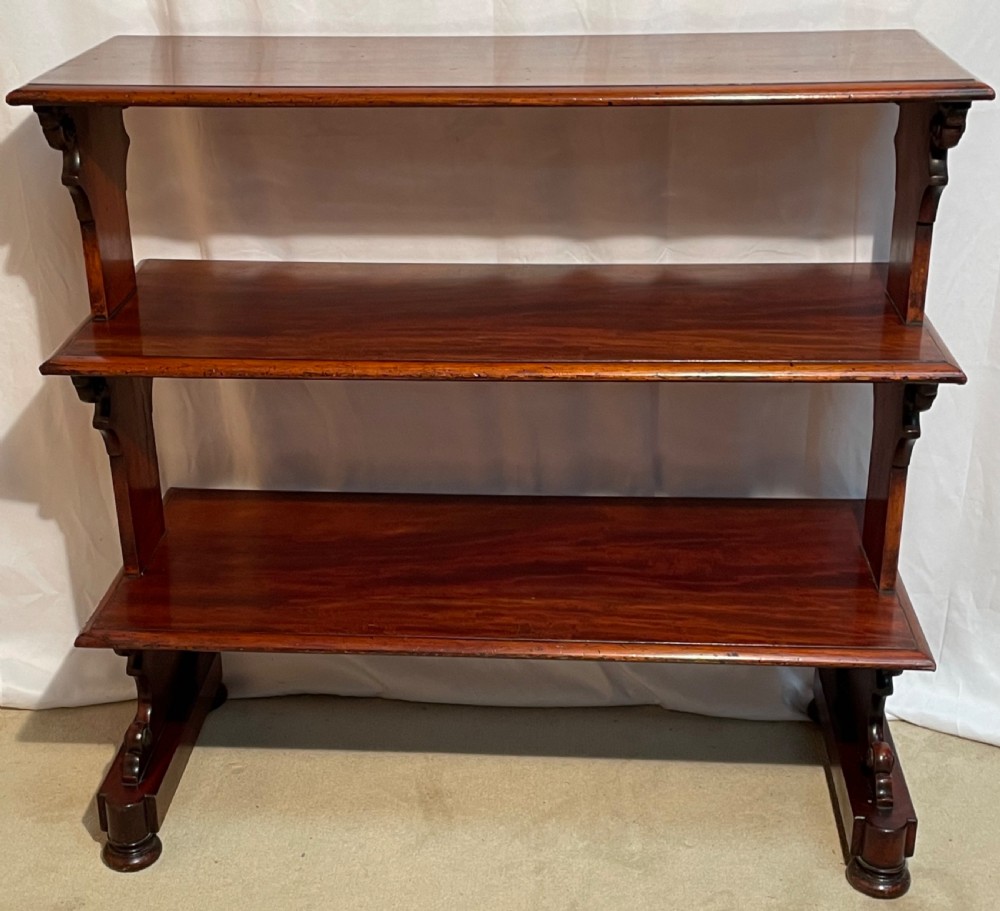 A three-tiered William IV mahogany dumb waiter featuring carved scroll supports with carved roundel details and a polished finish. View X