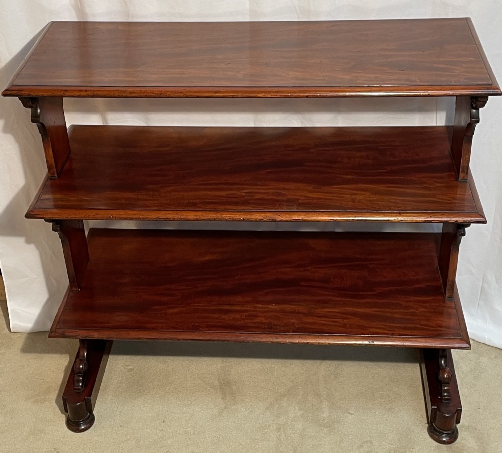 A three-tiered William IV mahogany dumb waiter featuring carved scroll supports with carved roundel details and a polished finish. View XI
