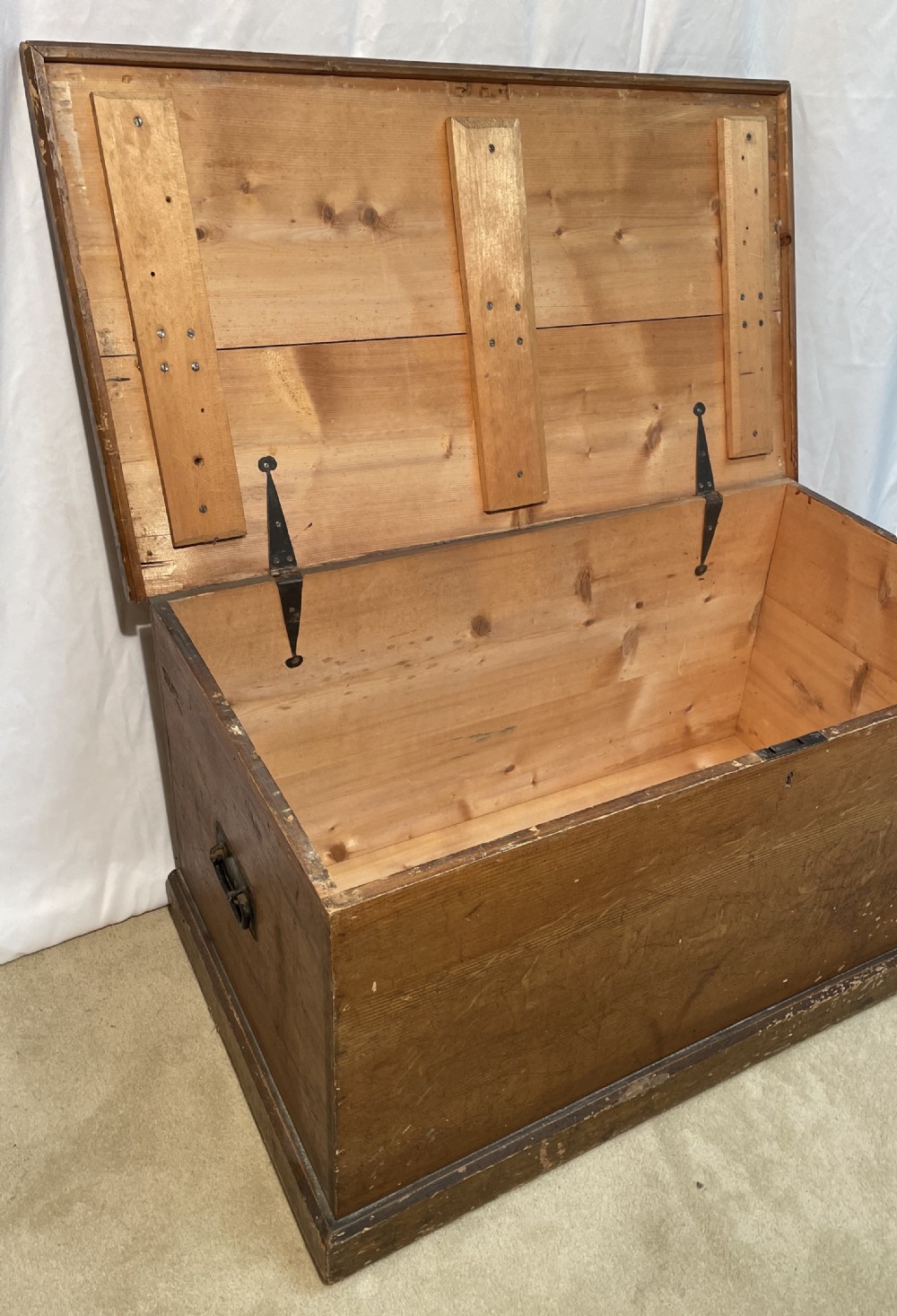 An open antique pine blanket box with a faux-grain painted exterior, exposed internal timber, and iron strap hinges. View III