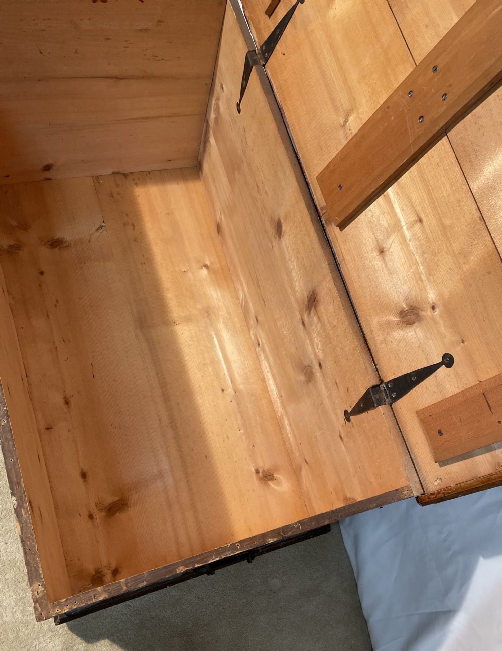 An open antique pine blanket box with a faux-grain painted exterior, exposed internal timber, and iron strap hinges. View V
