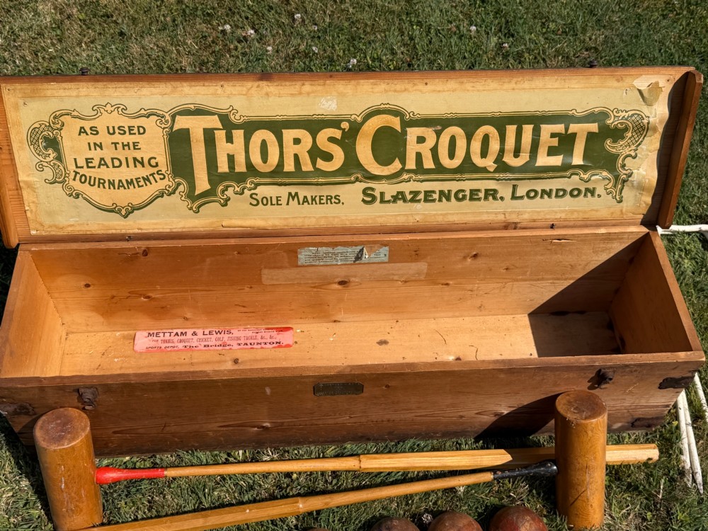 An open pine storage box with a Slazenger printed label displaying four wooden croquet mallets, coloured balls, metal hoops, and wooden pegs. View II
