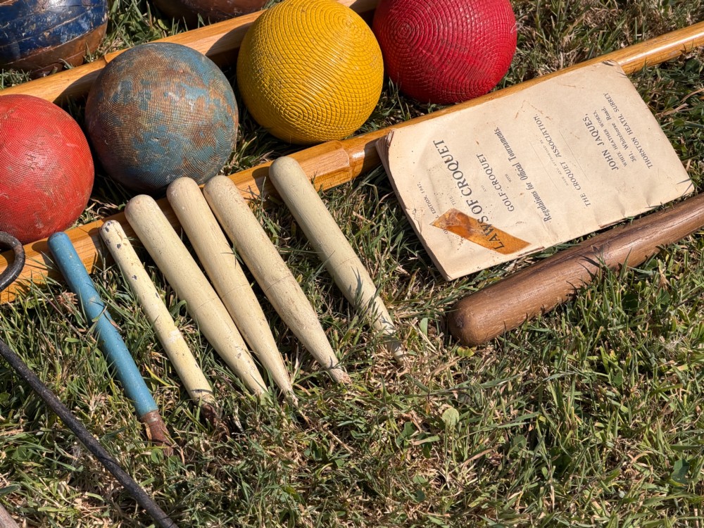 An open pine storage box with a Slazenger printed label displaying four wooden croquet mallets, coloured balls, metal hoops, and wooden pegs. View VIII